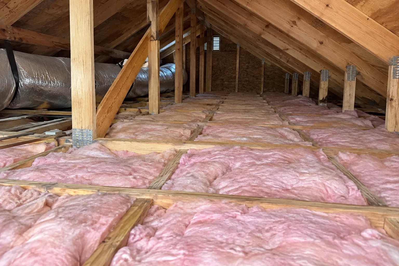 Fiberglass batt insulation installed between attic floor joists, providing full, even coverage across the space.