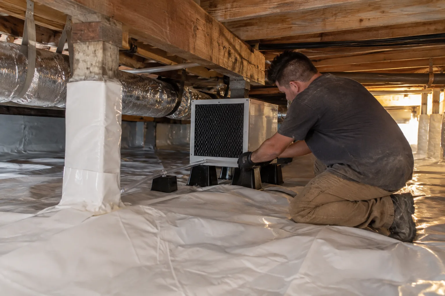 Installing an air filtration/exchange unit on risers inside an encapsulated crawl space to help control air quality and moisture.